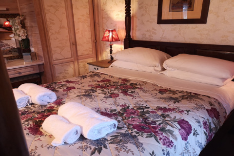 Camera da letto nella cabina Tore Petty, Regno Unito, con copriletto floreale e asciugamani arrotolati.