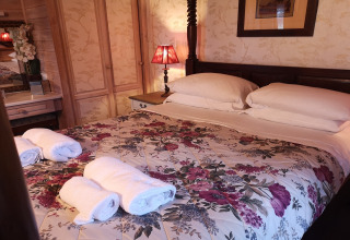 Camera da letto nella cabina Tore Petty, Regno Unito, con copriletto floreale e asciugamani arrotolati.