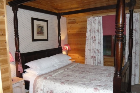 Camera da letto in cabina di legno con letto a baldacchino e tende floreali, Tore Petty, Regno Unito.