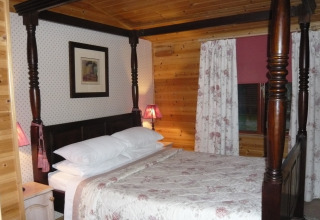 Camera da letto in cabina di legno con letto a baldacchino e tende floreali, Tore Petty, Regno Unito.