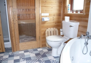 Bagno con pannelli in legno, wc, vasca e sauna in una baita chiamata 'Tore Petty' nel Regno Unito.