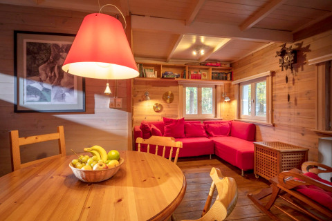 Soggiorno accogliente dello chalet Het Beerenbos in Belgio con divano rosso e interni in legno.