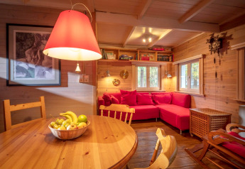 Knusse chaletruimte in Het Beerenbos, België met rode zetel, houten muren en fruitschaal op tafel.