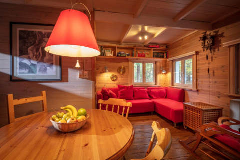 Soggiorno accogliente dello chalet Het Beerenbos in Belgio con divano rosso e interni in legno.