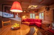 Acogedora sala de chalet en Het Beerenbos, Bélgica, con sofá rojo, madera y frutero sobre la mesa.