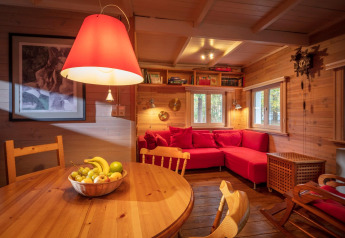 Acogedora sala de chalet en Het Beerenbos, Bélgica, con sofá rojo, madera y frutero sobre la mesa.
