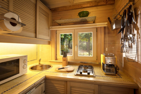 Accogliente cucina in legno con fornello, lavello e finestra sul bosco nello chalet Het Beerenbos, Belgio.