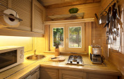 Sfeervolle houten keuken met kookplaat, spoelbak en boszicht in chalet Het Beerenbos, België.
