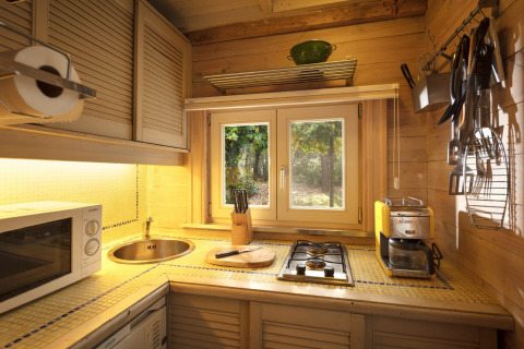 Accogliente cucina in legno con fornello, lavello e finestra sul bosco nello chalet Het Beerenbos, Belgio.