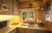 Acogedora cocina de madera con estufa, fregadero y ventana al bosque en chalet Het Beerenbos, Bélgica.