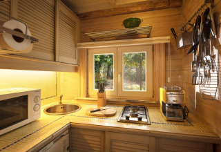 Accogliente cucina in legno con fornello, lavello e finestra sul bosco nello chalet Het Beerenbos, Belgio.