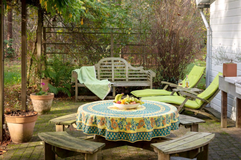 Accogliente patio allo chalet 'Het Beerenbos' in Belgio con tavolo, panche, sdraio e una fruttiera.