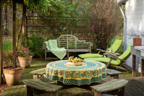 Accogliente patio allo chalet 'Het Beerenbos' in Belgio con tavolo, panche, sdraio e una fruttiera.