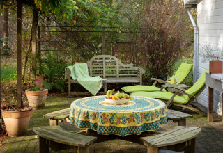 Accogliente patio allo chalet 'Het Beerenbos' in Belgio con tavolo, panche, sdraio e una fruttiera.