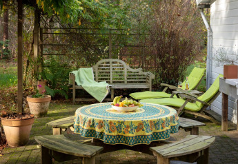 Acogedora terraza en el chalet 'Het Beerenbos' en Bélgica con mesa, bancos, tumbonas y frutero.
