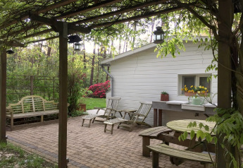 Buitenterras aan chalet Het Beerenbos in België met houten zitbank, ligstoelen en groene planten.