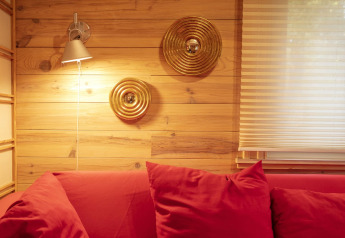 Acogedor rincón en el chalet Het Beerenbos, Bélgica, con sofá rojo, pared de madera y detalles dorados.