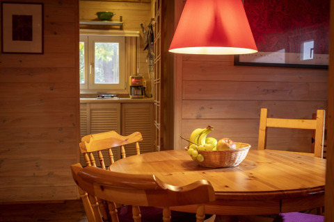 Accogliente sala da pranzo in legno presso lo chalet Het Beerenbos in Belgio con cesta di frutta a tavola.