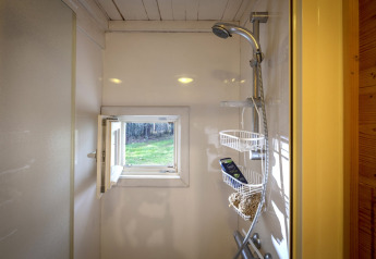 Ducha con pequeña ventana abierta al jardín en el chalet Het Beerenbos en Bélgica, luz natural entrando.