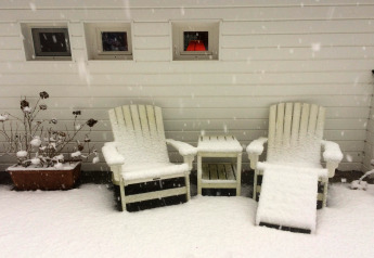 Twee met sneeuw bedekte stoelen en een tafeltje aan chalet 'Het Beerenbos' in België tijdens de winter.