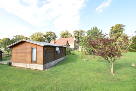 Een houten chalet en groene tuin met bomen bij Platz im Grünen 2, genomen op een zonnige dag.