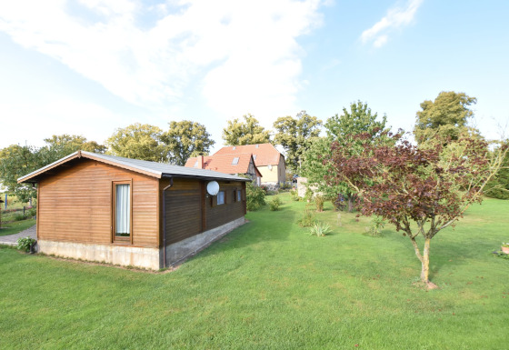 Een houten chalet en groene tuin met bomen bij Platz im Grünen 2, genomen op een zonnige dag.