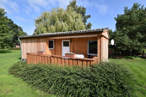 Wooden cabin with porch and garden, surrounded by greenery, at Bungalow complex Gänseblümchen 2.