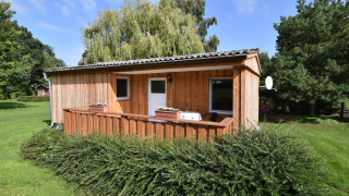 Wooden cabin with porch and garden, surrounded by greenery, at Bungalow complex Gänseblümchen 2.