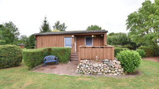 Bungalow en bois avec terrasse en pierre, banc bleu et jardin, dans le complexe Gänseblümchen 7.