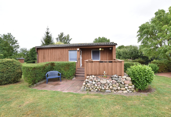 Wooden bungalow with a stone terrace, blue bench and garden at Bungalow complex Gänseblümchen 7.