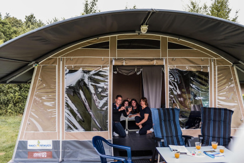 Famille réunie dans une tente safari au Resort Echternacherbrück 1 avec chaises et boissons en extérieur.