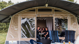 Famille réunie dans une tente safari au Resort Echternacherbrück 1 avec chaises et boissons en extérieur.