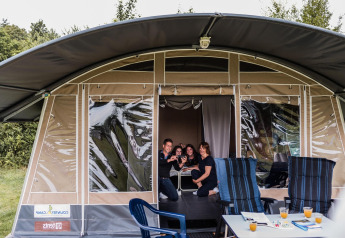 Gezin samen in een safaritent bij Resort Echternacherbrück 1 met stoelen en drankjes buiten.