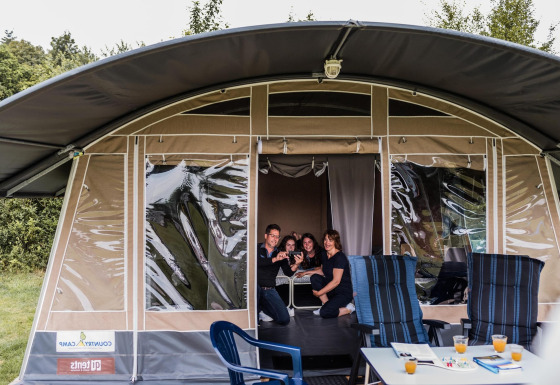 Famille réunie dans une tente safari au Resort Echternacherbrück 1 avec chaises et boissons en extérieur.