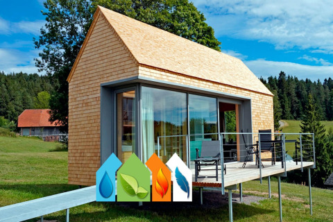 Haus Wasser, a modern cabin with wood siding, large windows, deck, green landscape, and eco-icons displayed.
