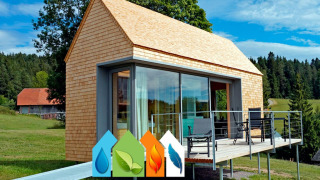 Haus Wasser, cabaña moderna de madera con ventanales y terraza, rodeada de naturaleza y símbolos ecológicos.
