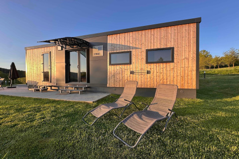 Casa tiny moderna en Holiday Village SEEBLICK con fachada de madera, terraza y tumbonas, Alemania.