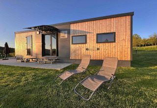 Moderne tiny house in SEEBLICK vakantiedorp met houten gevel, terras en ligstoelen in Duitsland.
