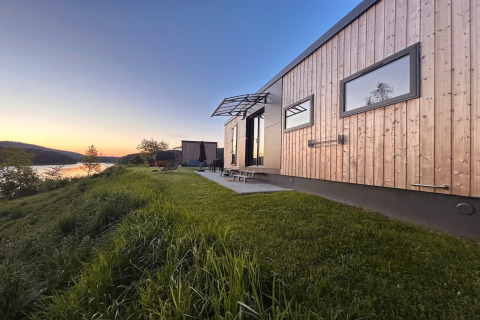 Modern tiny house by Lake Eixendorfer at sunset, featuring a patio and scenic waterfront view.