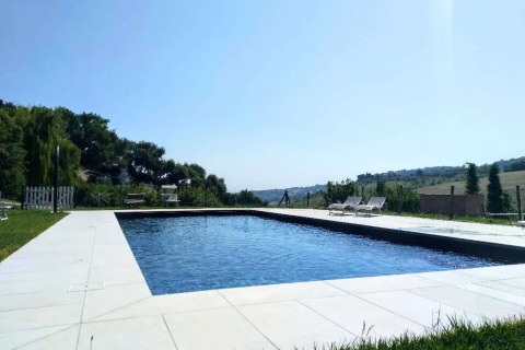 View of a swimming pool at a safari tent site, with lounge chairs and scenic landscape in the background.