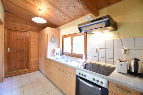Lichte houten keuken in een chalet bij Platz im Grünen 2, Duitsland, met moderne toestellen en raam.