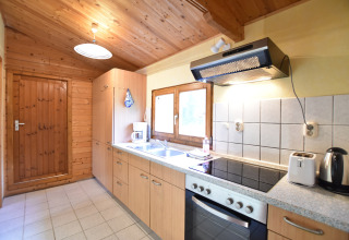 Lichte houten keuken in een chalet bij Platz im Grünen 2, Duitsland, met moderne toestellen en raam.