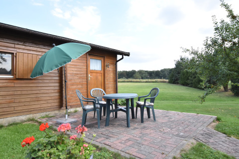 Terras bij houten huisje met tuinmeubilair en parasol, gelegen in het groen in Duitsland.