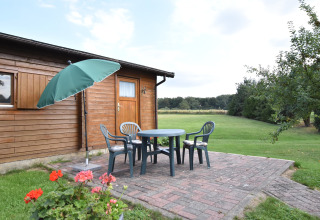 Terras bij houten huisje met tuinmeubilair en parasol, gelegen in het groen in Duitsland.