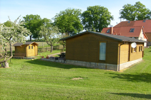 Houten vakantiewoning ‘Platz im Grünen 2’ in Duitsland, met tuin, bomen en huizen in de omgeving.