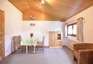 Woonkamer van ‘Platz im Grünen 2’ hut in Duitsland met houten meubels en uitnodigende uitstraling.