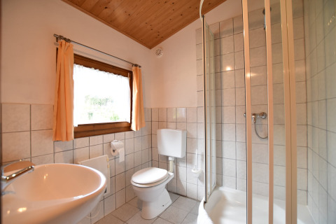 Lichte badkamer in de hut Platz im Grünen 2 in Duitsland met douche, wastafel, toilet en raam.