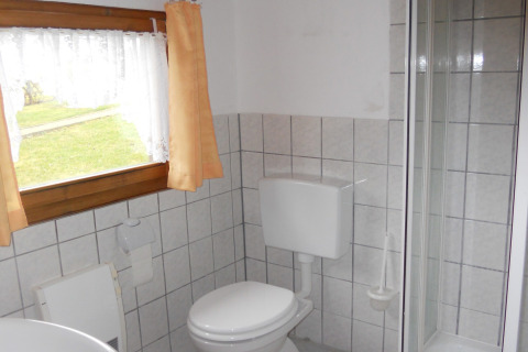 Badkamer met toilet, douche en raam met gordijn in een hut bij Platz im Grünen 2, Duitsland.
