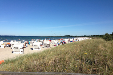 Strandscène met strandstoelen en mensen dicht bij de hut Platz im Grünen 2 aan de Duitse kust.