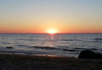 Sunset over the sea seen from the shore at the cabin named 'Platz im Grünen 2' in Germany.